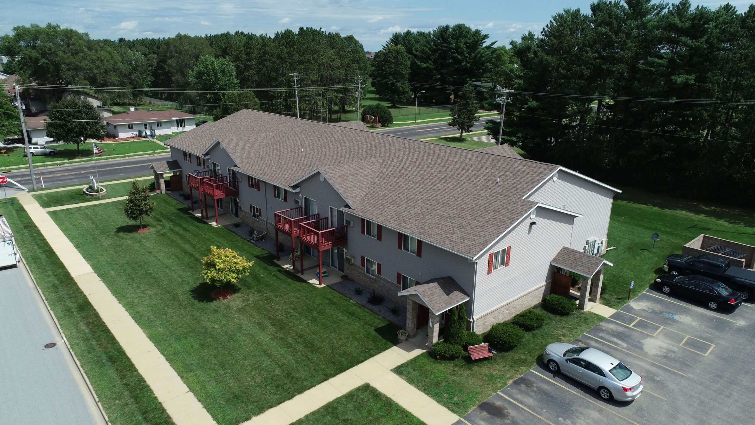 Aerial view of modern gray apartment building with red balconies and parking lot