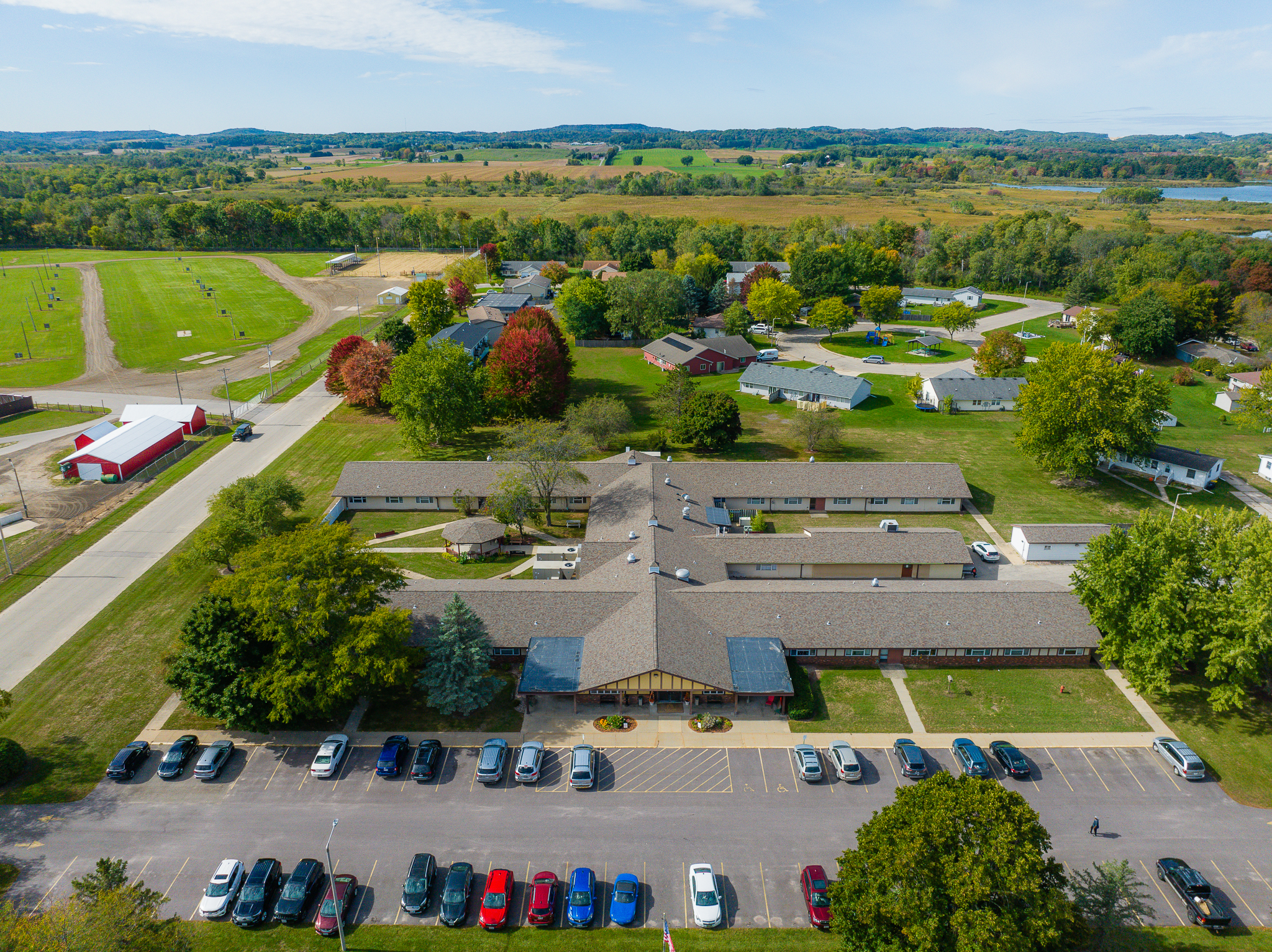 Aerial view of a large rural building complex surrounded by trees and fields