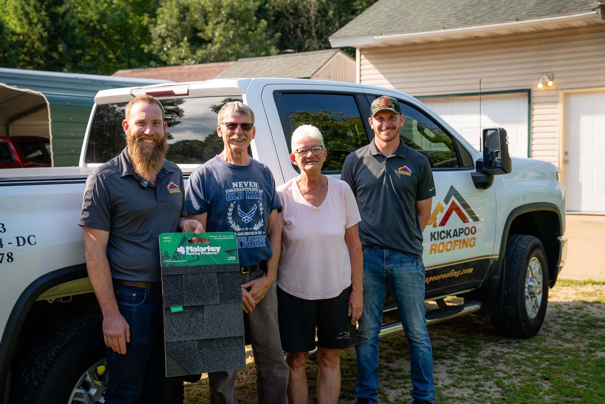 Group photo with roofing contractors and couple in front of Kickapoo Roofing truck.